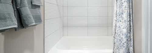 Bathroom at AMLI Bellevue Park apartments with bathtub shower with large white tile surround and flowered shower curtain