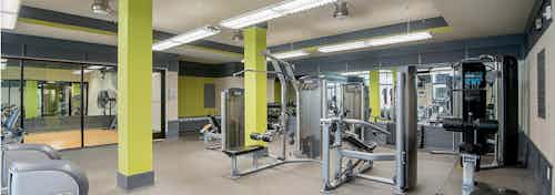Interior of the fitness center at AMLI Old 4th Ward apartment with treadmills and weight machines and vibrant walls