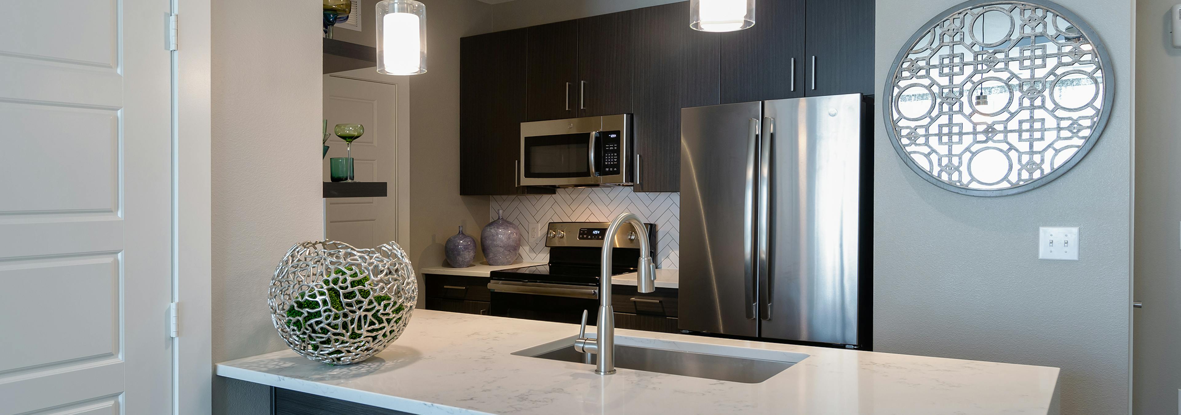 AMLI South Shore apartment kitchen with stainless steel appliances and quartz countertops with light ceramic tile backsplash