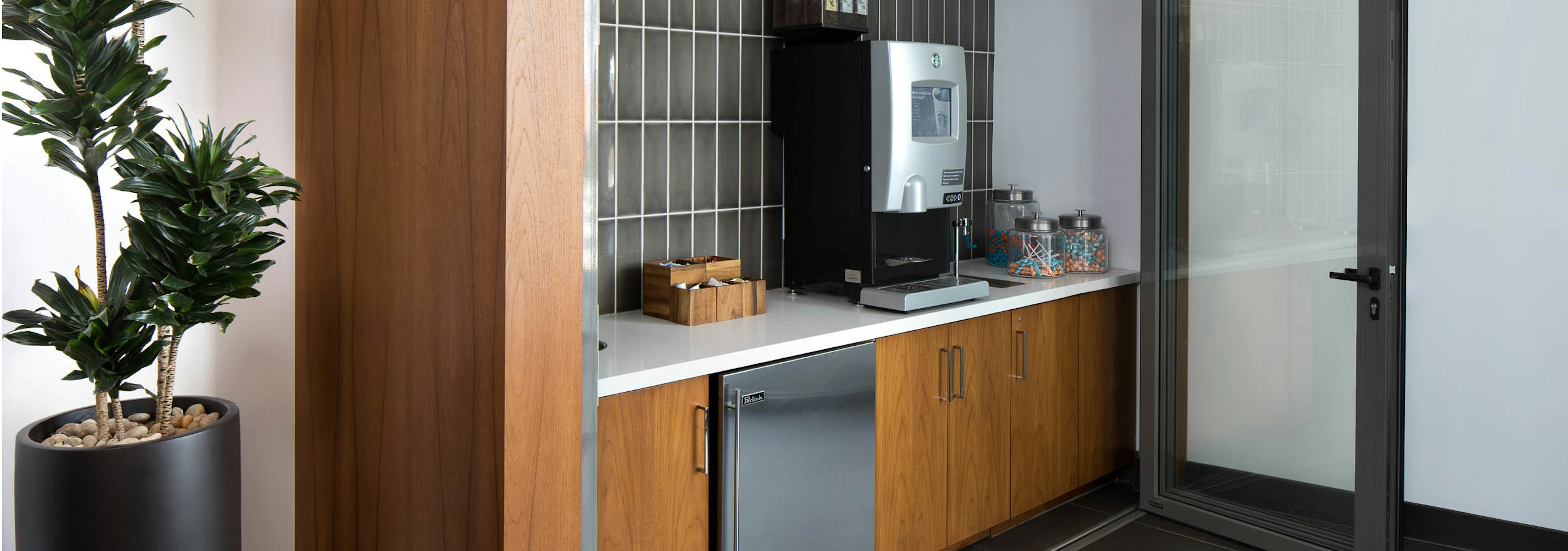 Interior of Starbucks java bar at AMLI Uptown Orange apartments with accordion door and gray tile backsplash and small fridge