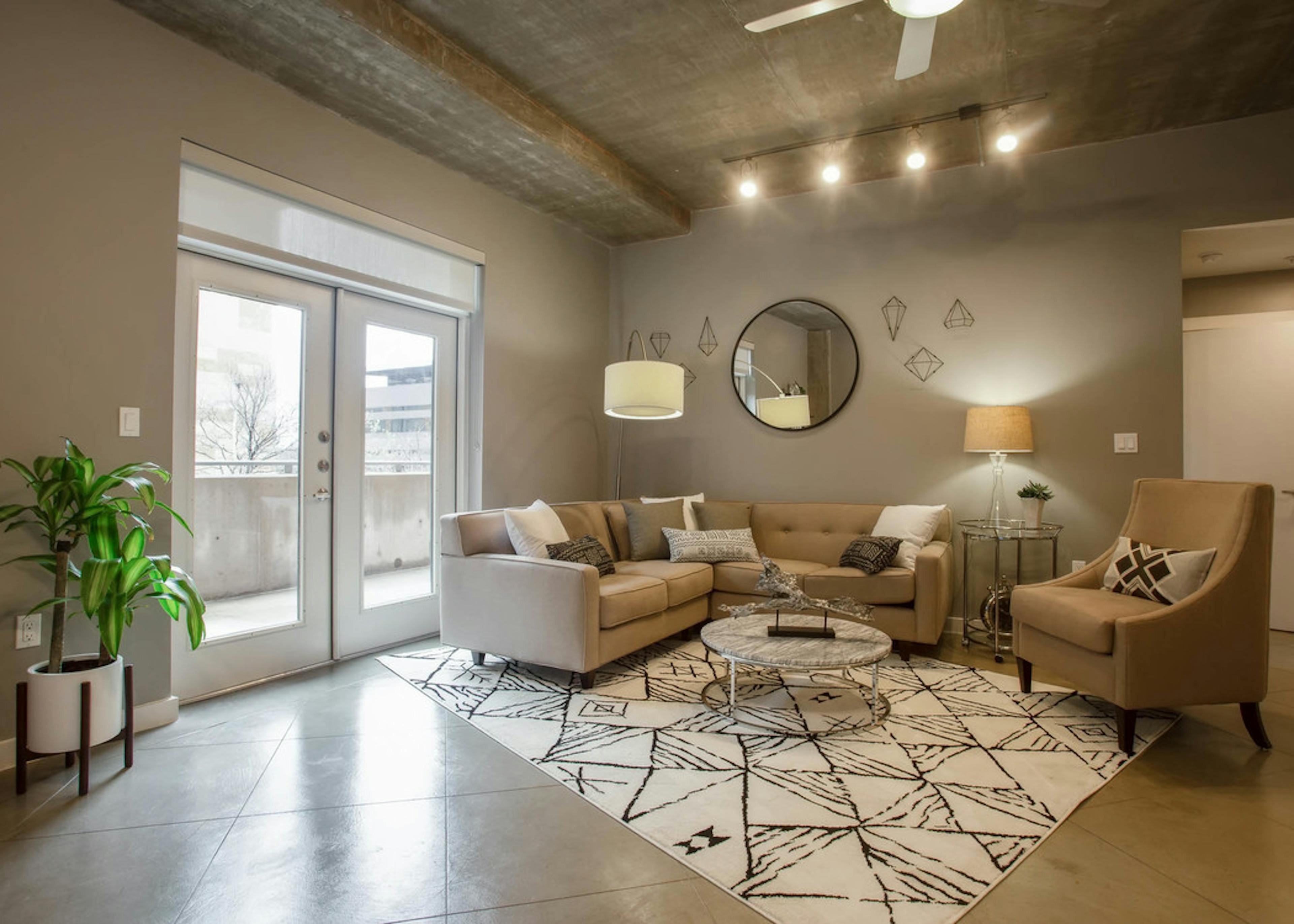 Interior of AMLI Downtown living room with neutral colored seating in front of balcony doors with bright daytime view