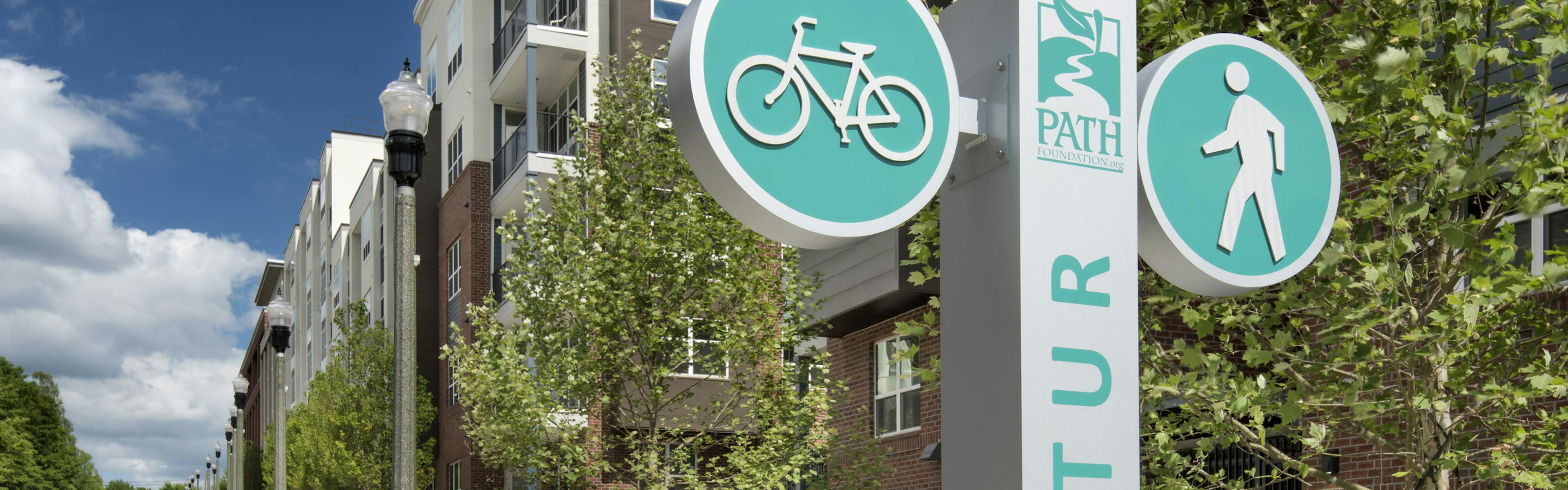 Exterior daytime view of AMLI Decatur apartments with the PATH Fountain’s bike path and sidewalk in front of the building 