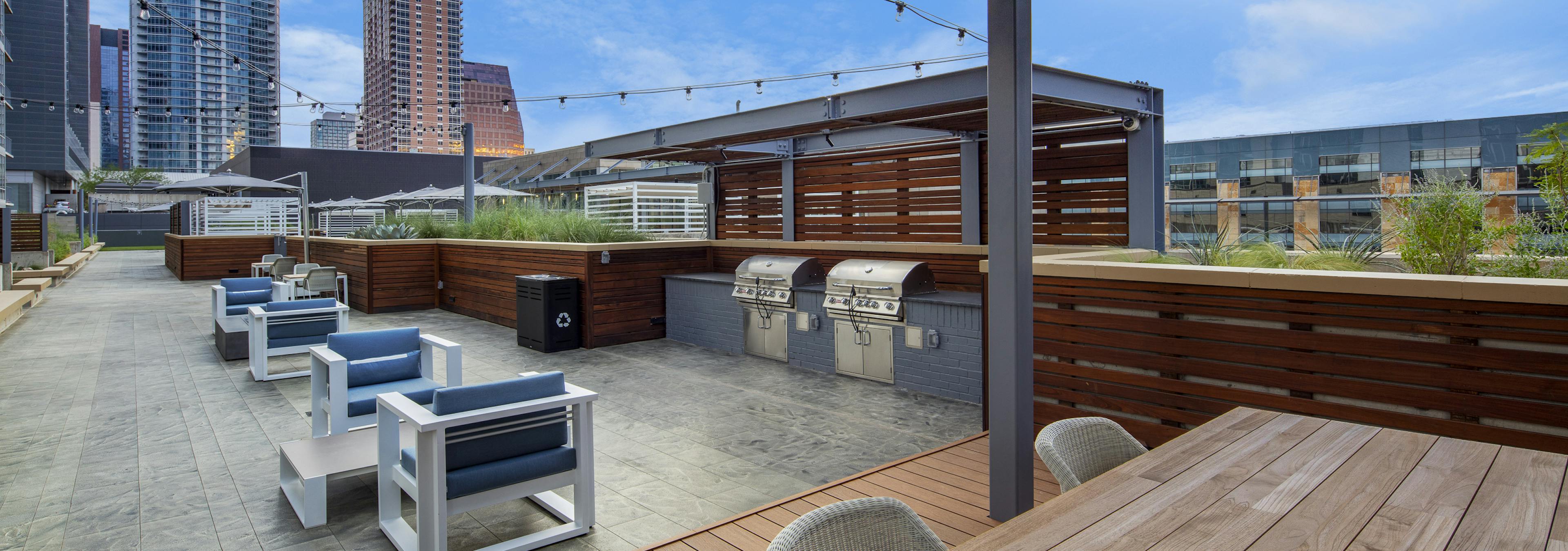 Sunset view of AMLI on 2ND outdoor grill area on Skye deck with surrounding seating area and suspended string lights