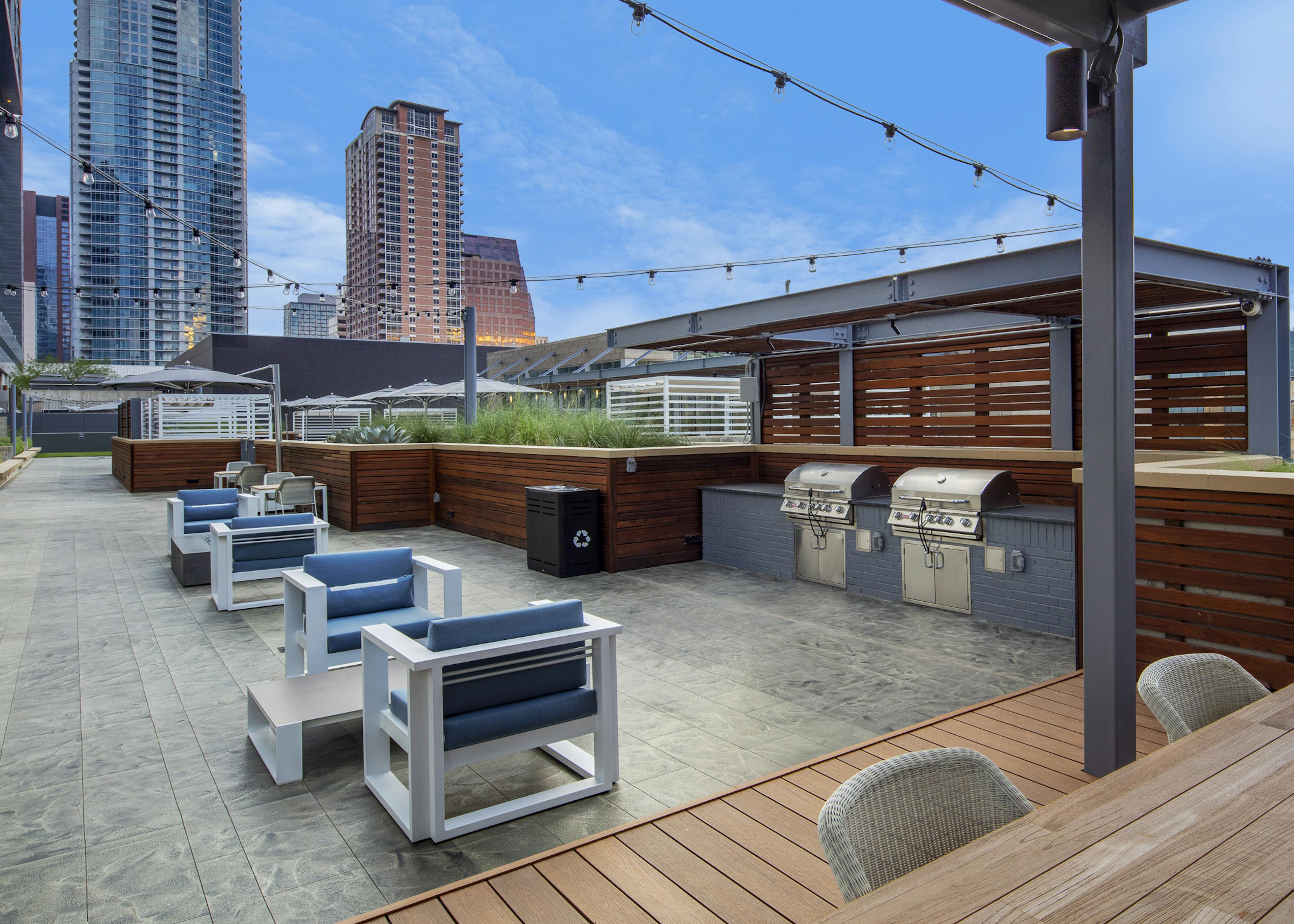 Sunset view of AMLI on 2ND outdoor grill area on Skye deck with surrounding seating area and suspended string lights
