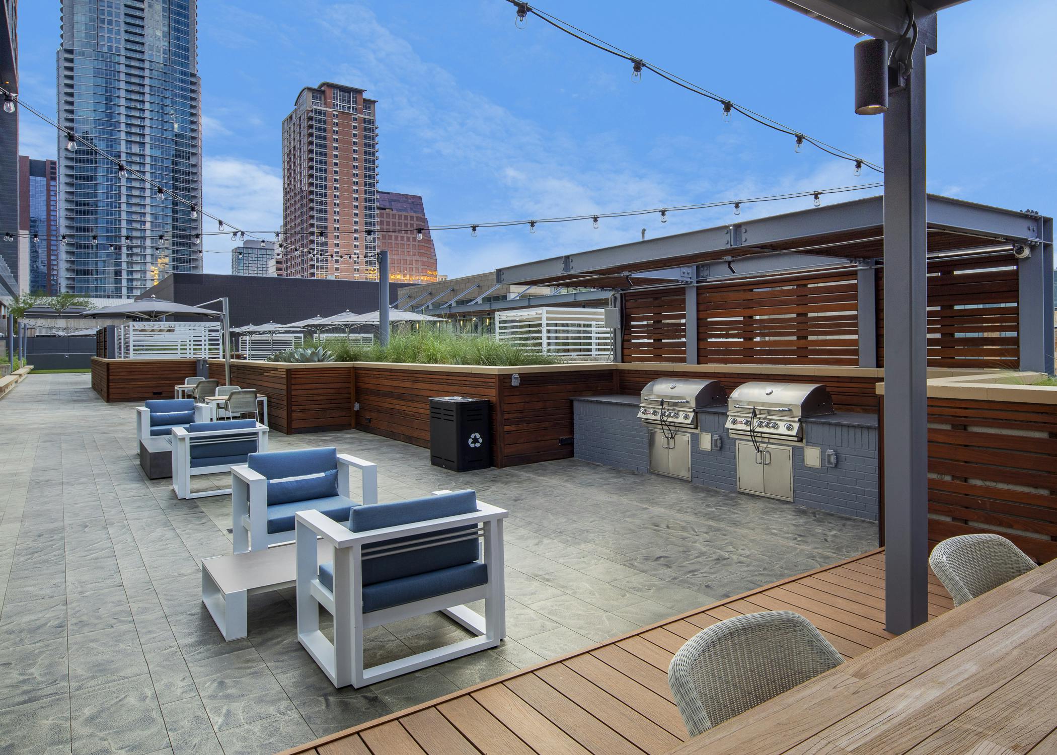 Sunset view of AMLI on 2ND outdoor grill area on Skye deck with surrounding seating area and suspended string lights