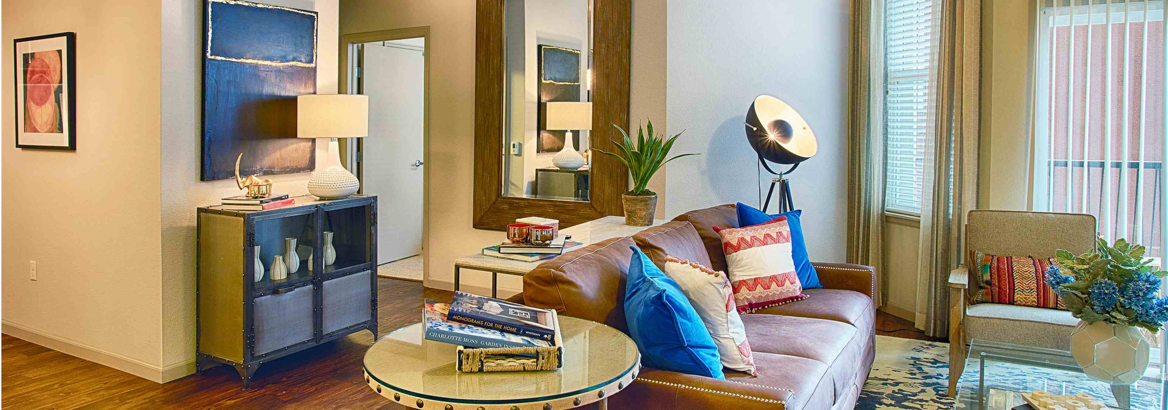 Interior view of a living room at AMLI Denargo Market apartments with lamps and a couch and chair and a look in the bedroom