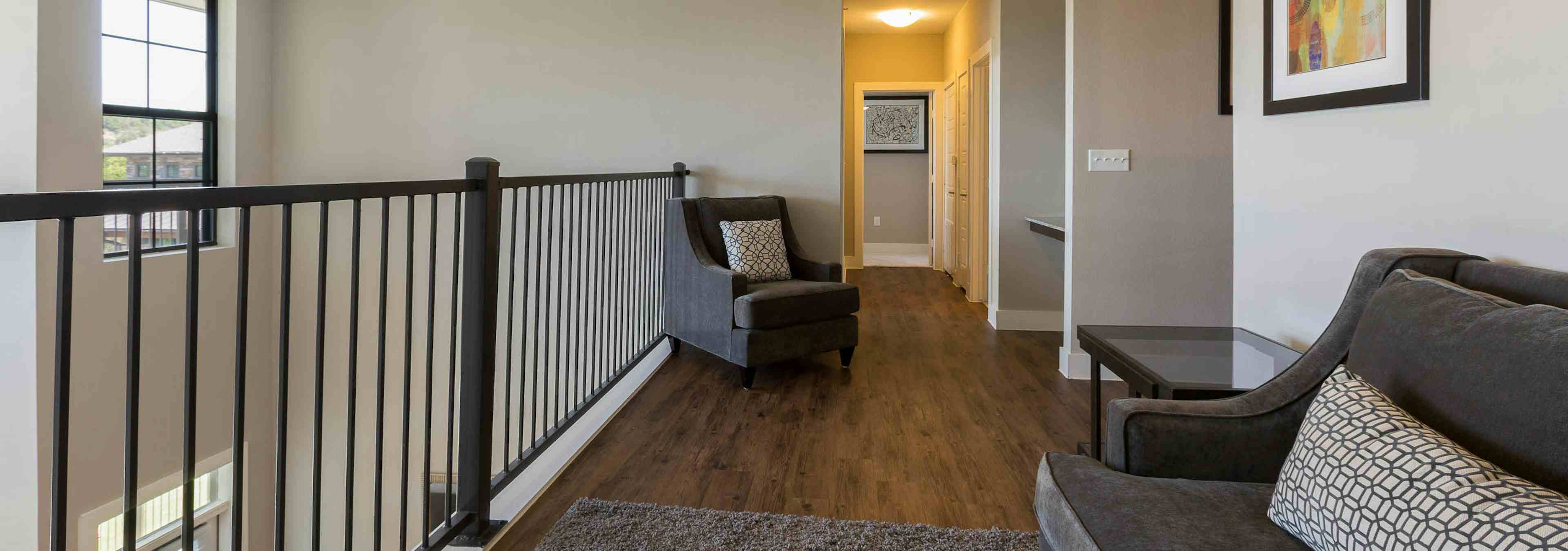 Interior of AMLI Covered Bridge townhome second floor hallway with a seating area and dark brown plank flooring