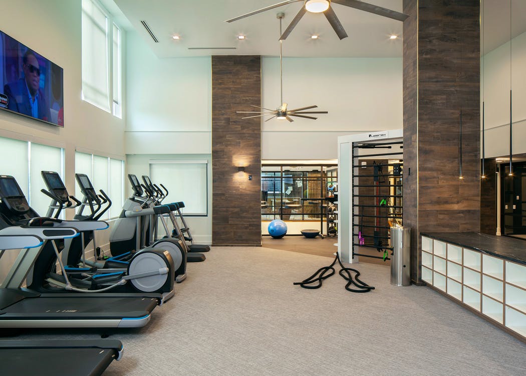 Fitness center at AMLI Riverfront Green apartments with multiple treadmills and elliptical machines with overhead fans