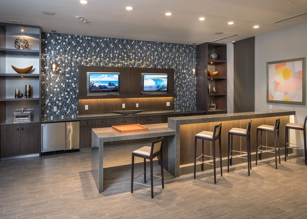 Interior of theatre at AMLI 3464 kitchen area with barstool seating and ample counter space with a patterned backsplash