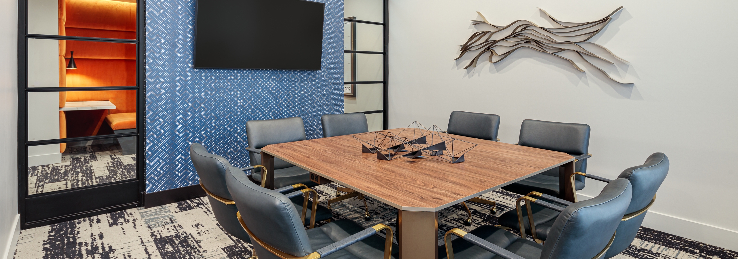AMLI Addison resident conference room with large wooden desk and eight surrounding leather chairs with patterned carpet floor