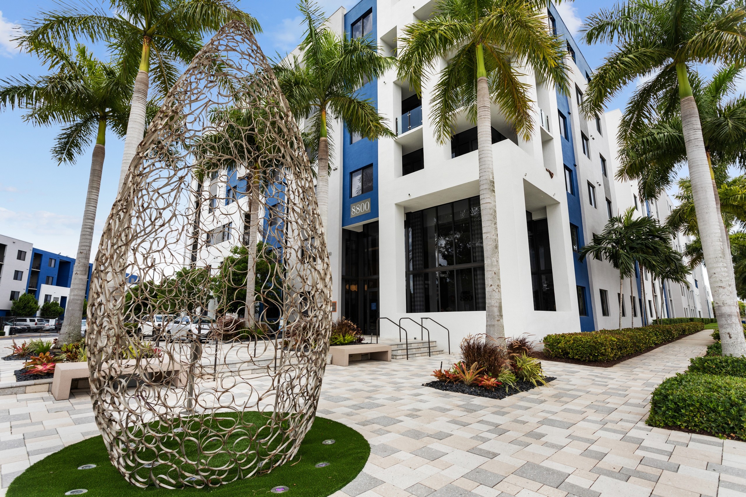 Leasing office at AMLI 8800 with blue painted accents and benches with tropical landscape and wire sculpture 
