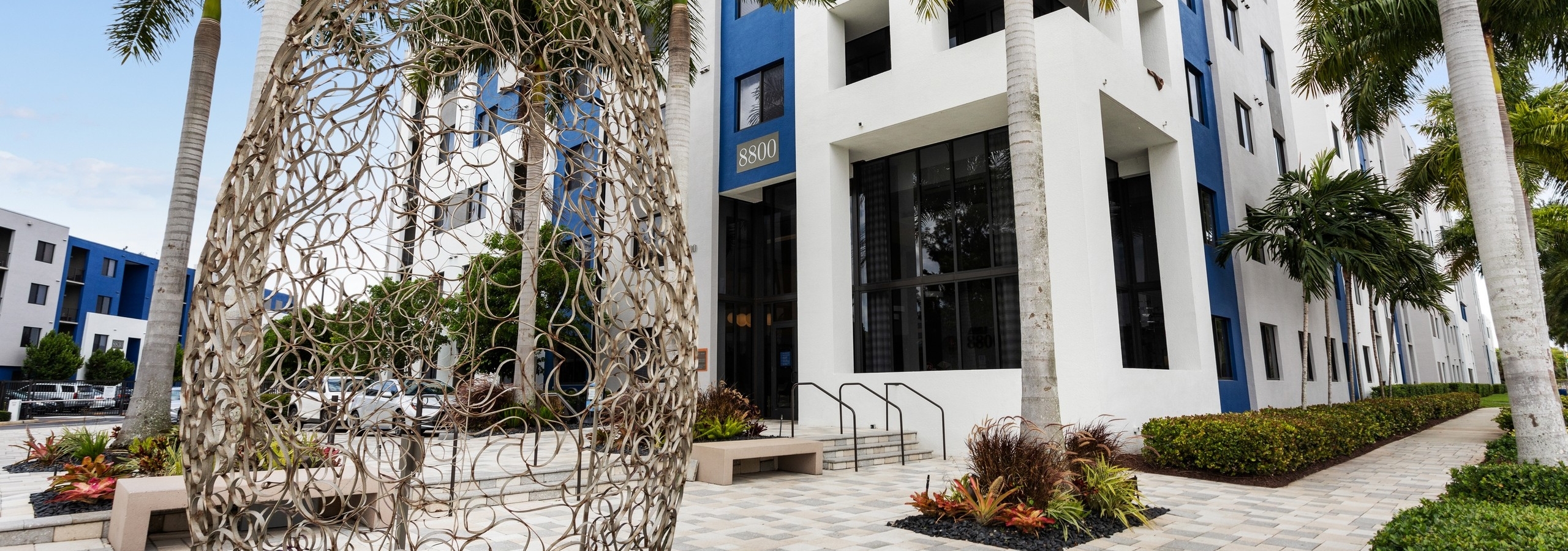 Leasing office at AMLI 8800 with blue painted accents and benches with tropical landscape and wire sculpture