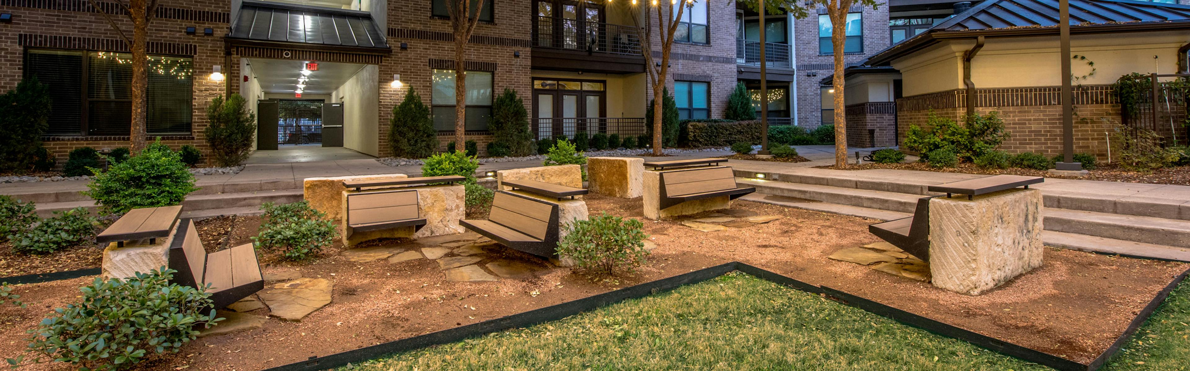 Nighttime courtyard with grass and seating and landscaping and buildings in background at AMLI at the Ballpark apartments