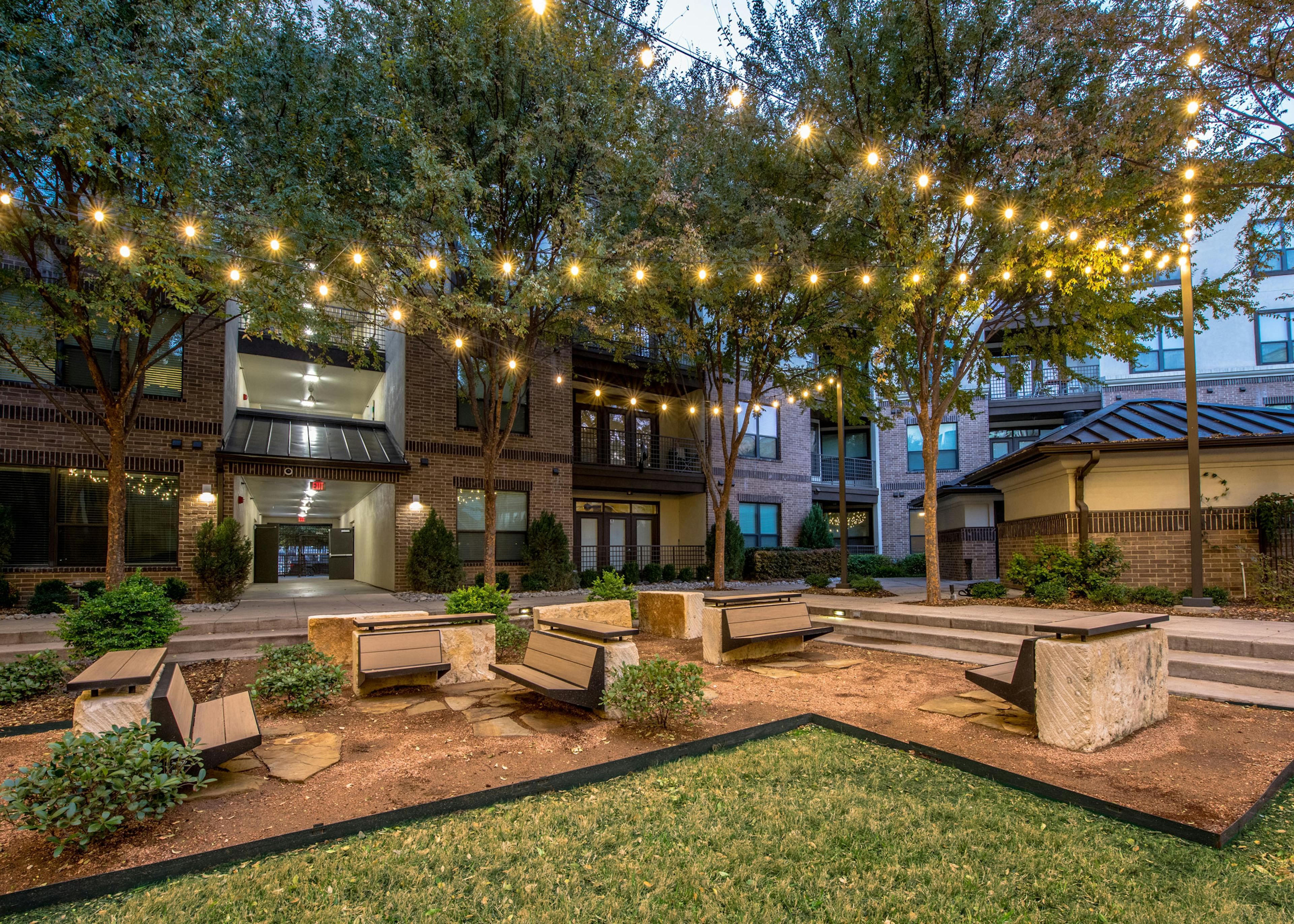 Nighttime courtyard with grass and seating and landscaping and buildings in background at AMLI at the Ballpark apartments