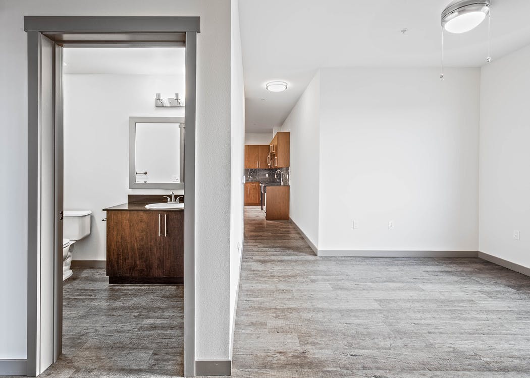 Interior view of bathroom and kitchen from the living room of a AMLI Mark24 apartment with dark cabinets light floors