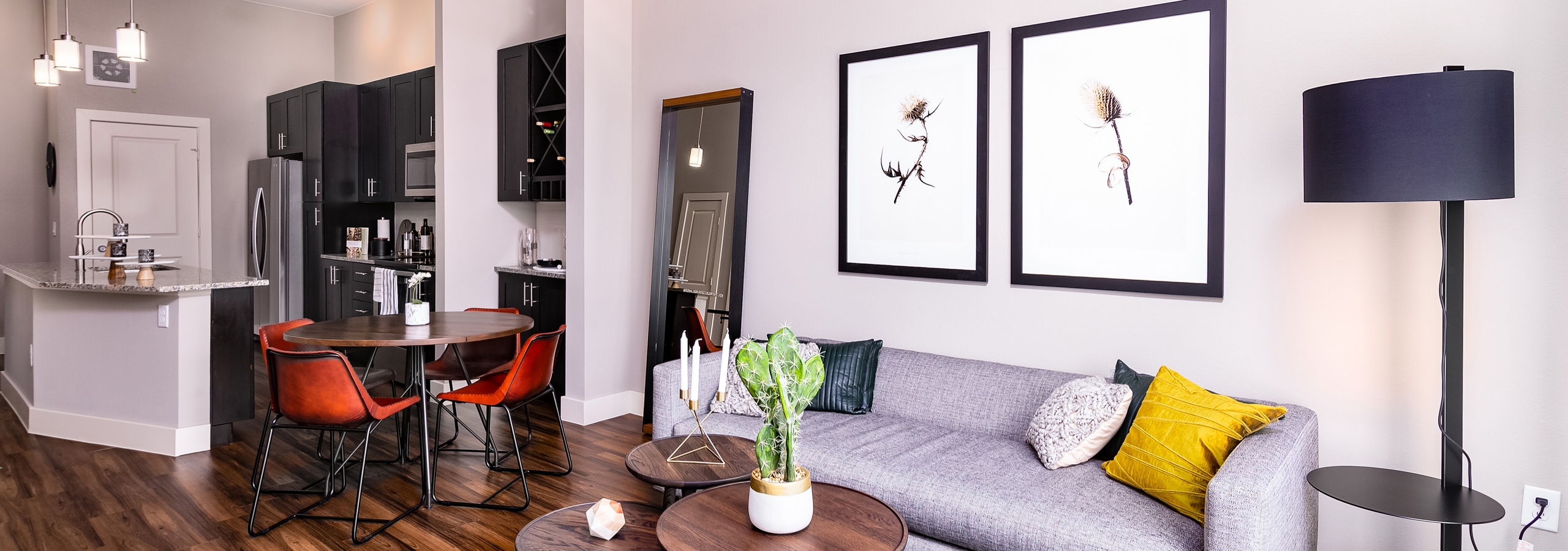 Interior of furnished living room, round dining table and kitchen with dark cabinets at AMLI Littleton Village apartments