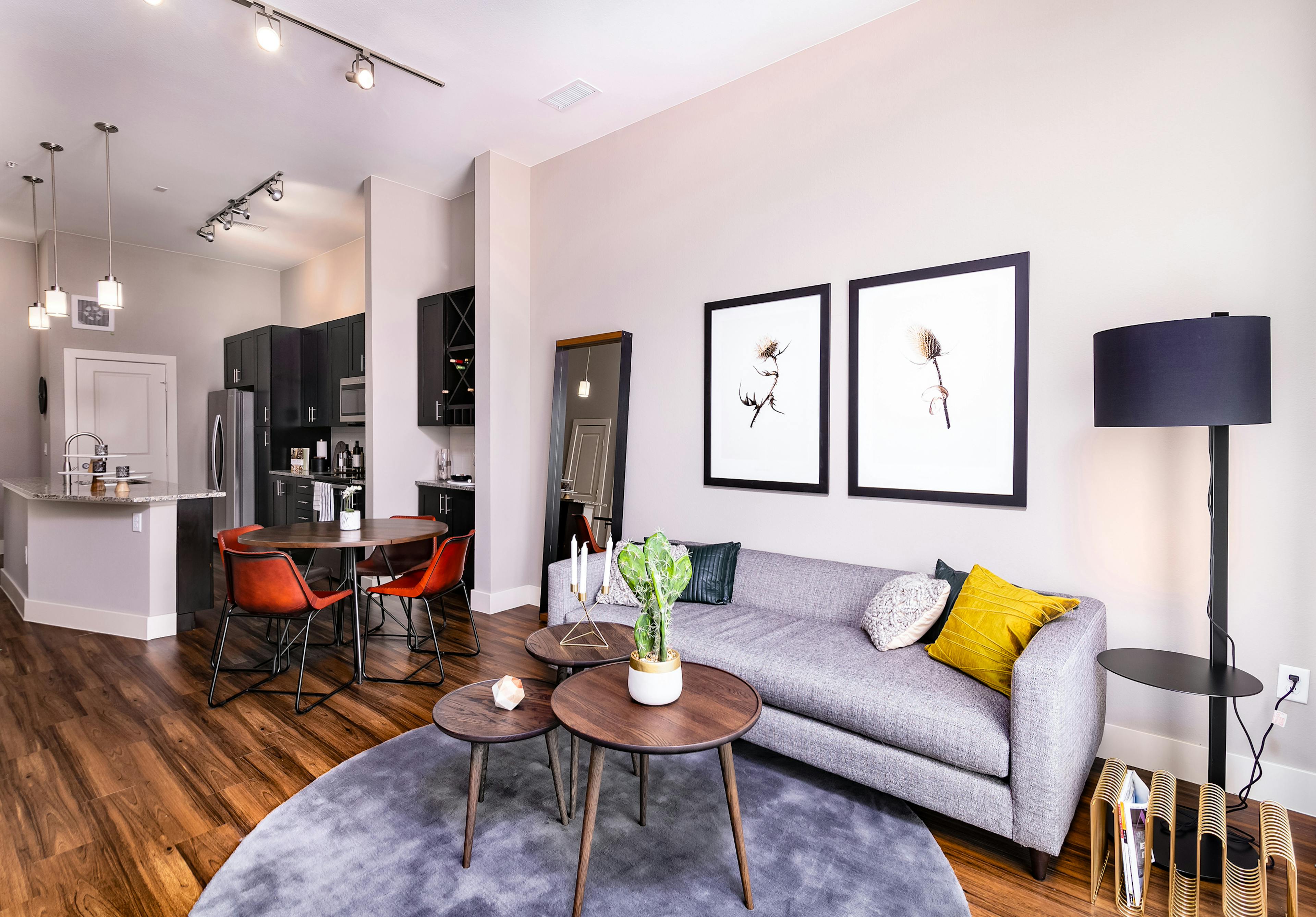 Interior of furnished living room, round dining table and kitchen with dark cabinets at AMLI Littleton Village apartments