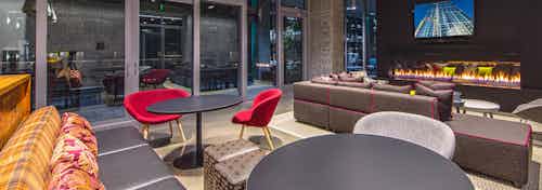 Interior club-room of AMLI Arc with spacious seating with colorful pillows large tv wall mounted fireplace and access to patio