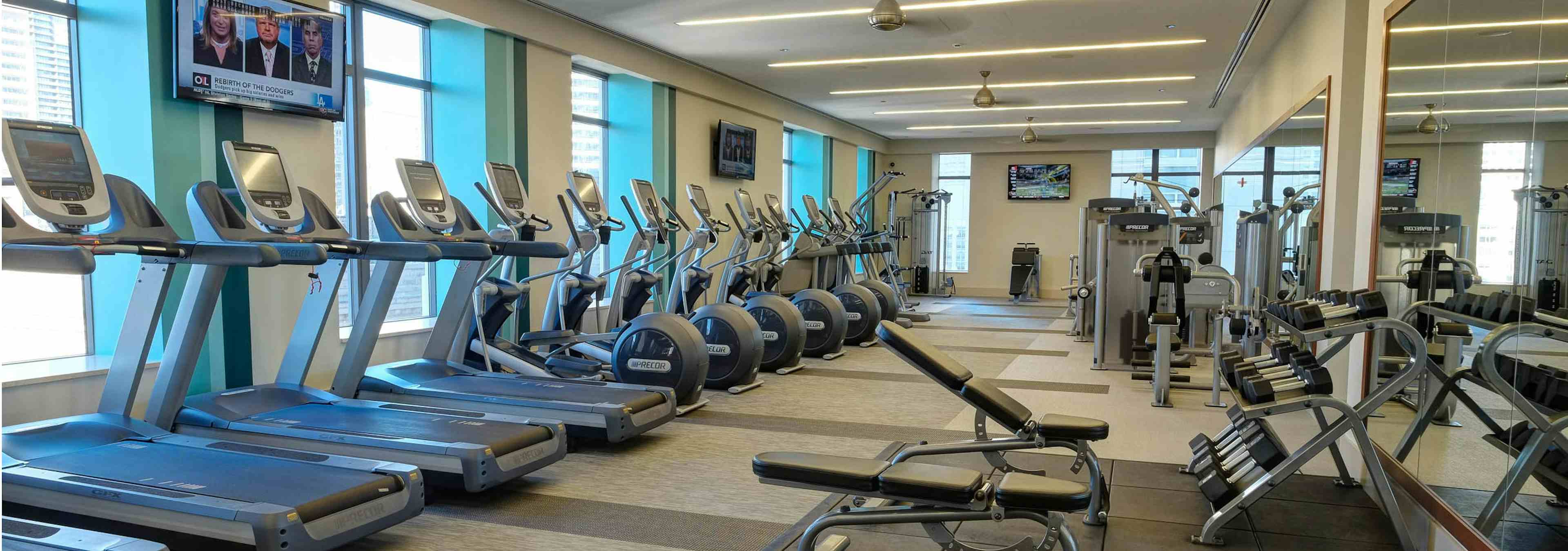 AMLI River North fitness center with treadmills along the wall and an area with shelved dumbbells in front of a mirror