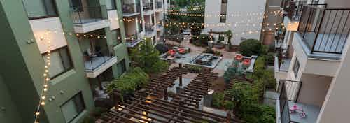 Overhead dusk view of AMLI Ponce Park courtyard with sitting area and fountainand lit hanging lights