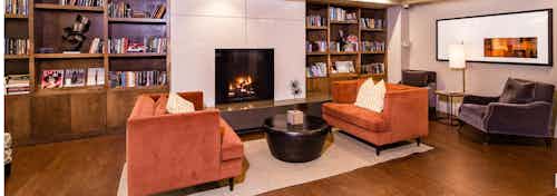 Interior view of library study lounge with two orange suede sofas, bookshelves and fireplace at AMLI RidgeGate apartments