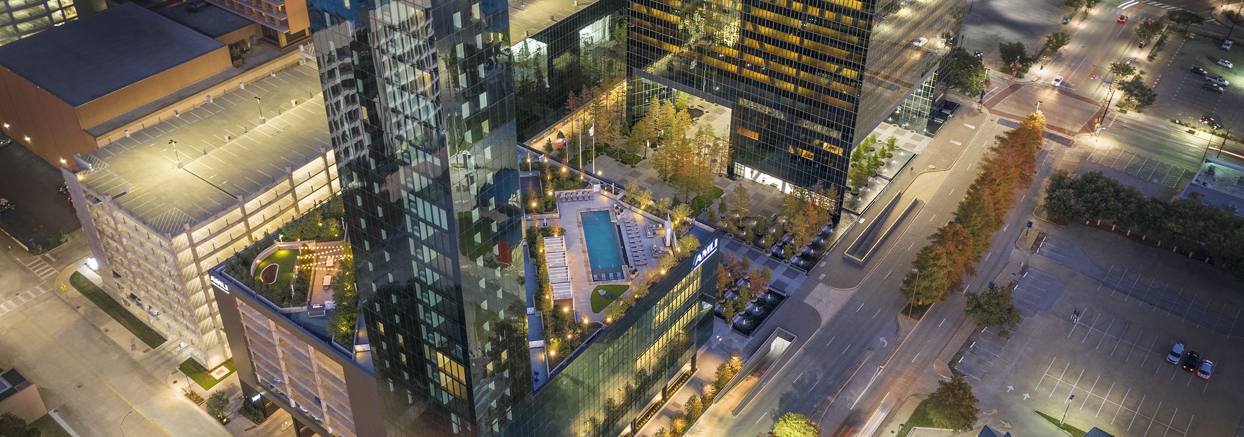 Night aerial view of AMLI Fountain Place apartment building with view of rooftops and Fountain Place office building