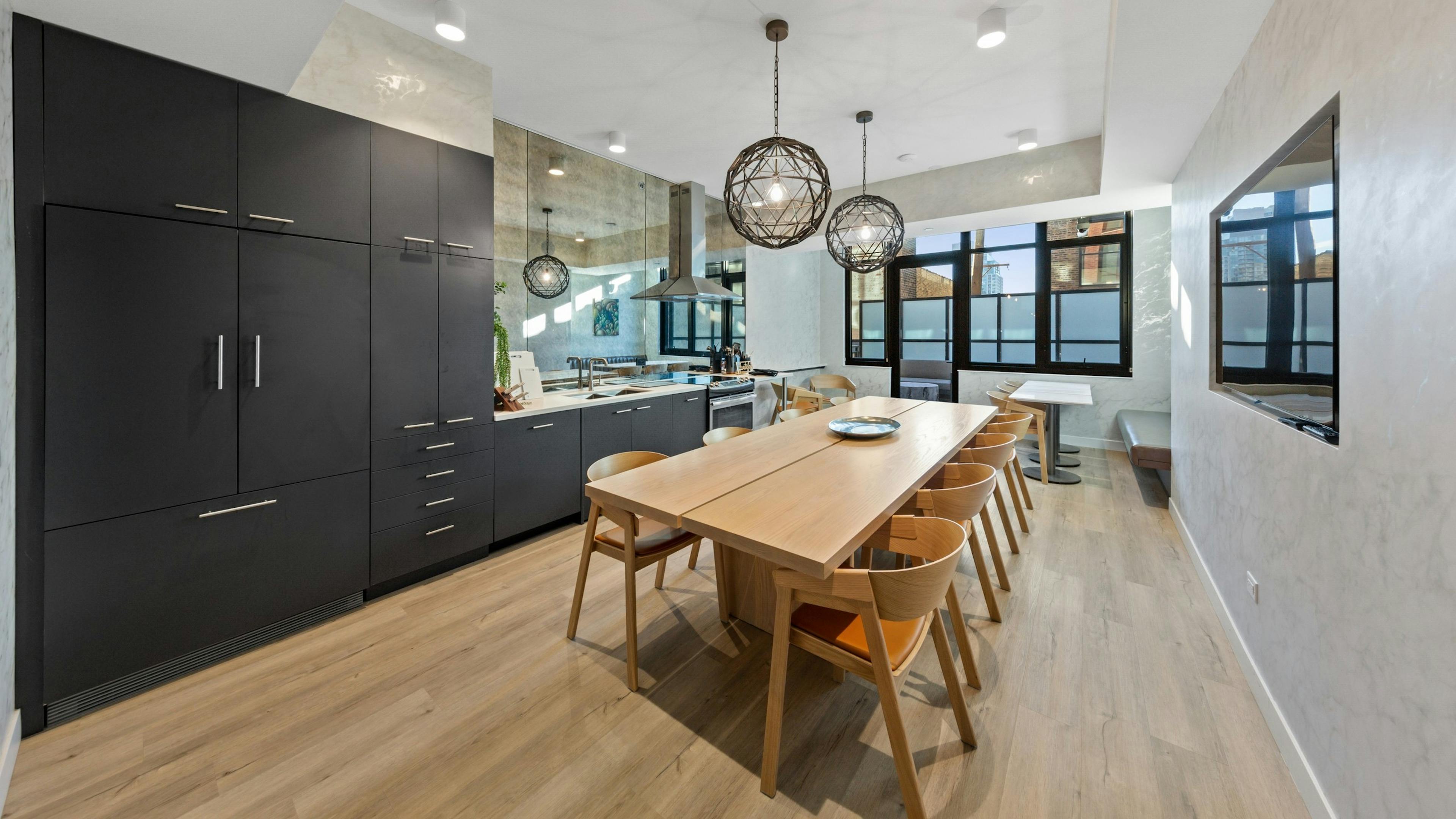 Modern dining room amenity at AMLI 808 featuring light flooring with industrial light fixtures and dark cabinetry