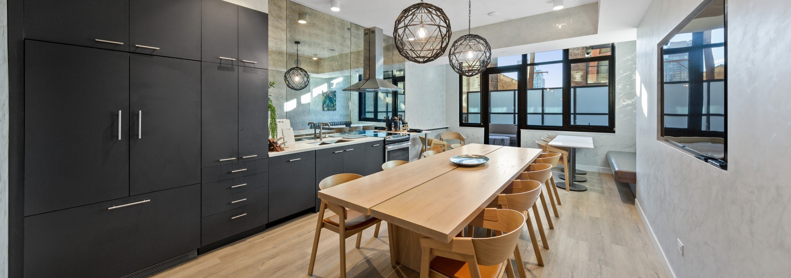 Modern dining room amenity at AMLI 808 featuring light flooring with industrial light fixtures and dark cabinetry