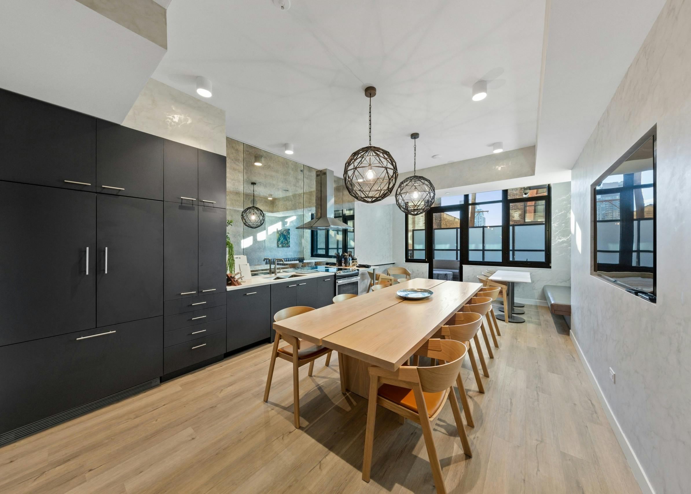 Modern dining room amenity at AMLI 808 featuring light flooring with industrial light fixtures and dark cabinetry