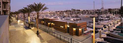 Evening view of walking promenade adorned with palm trees, lit up boat house facing marina at AMLI Marina Del Rey apartments