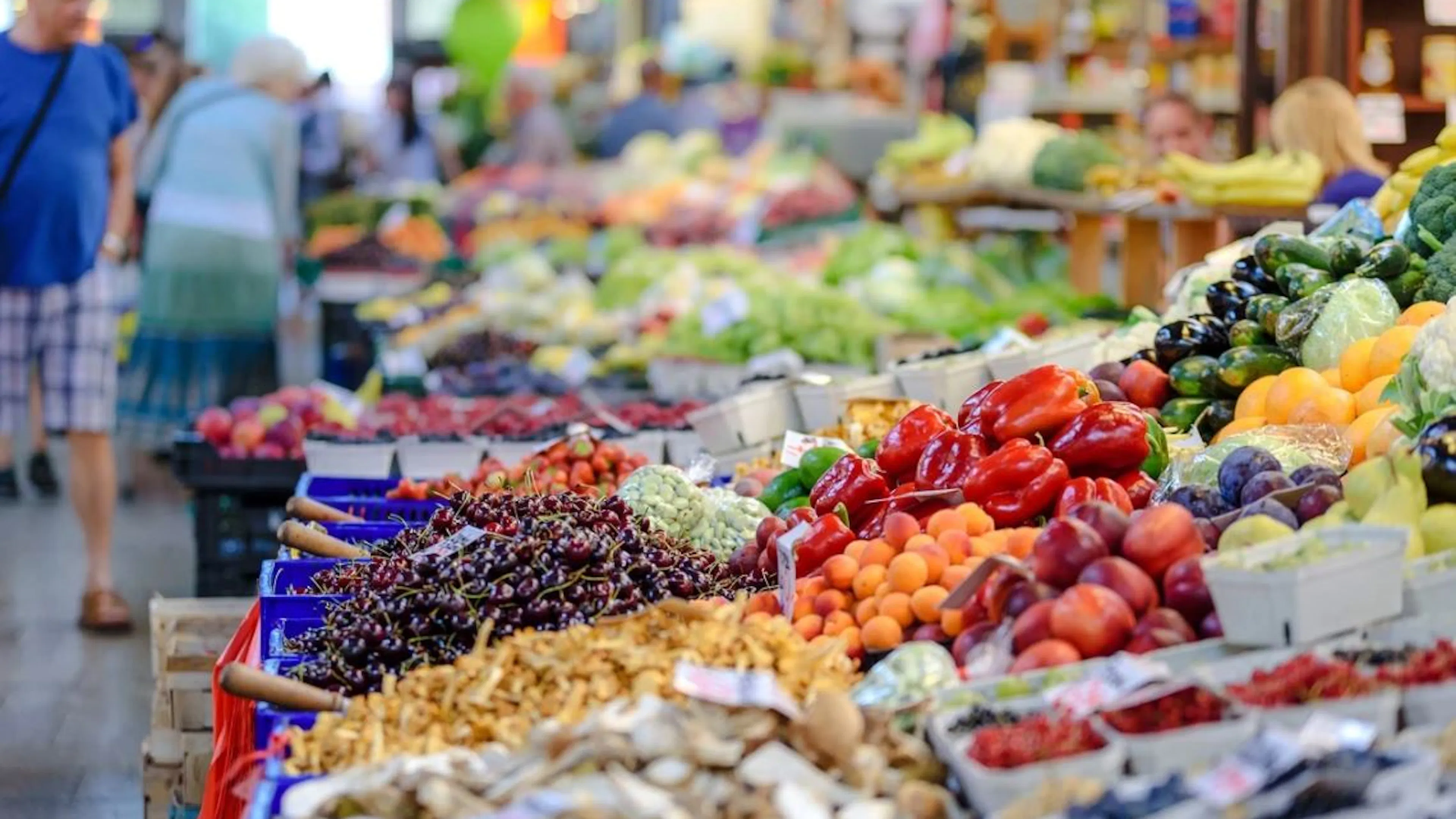 A long row of farmers market stands absolutely covered with a bright assortment of colorful fruits and vegetables