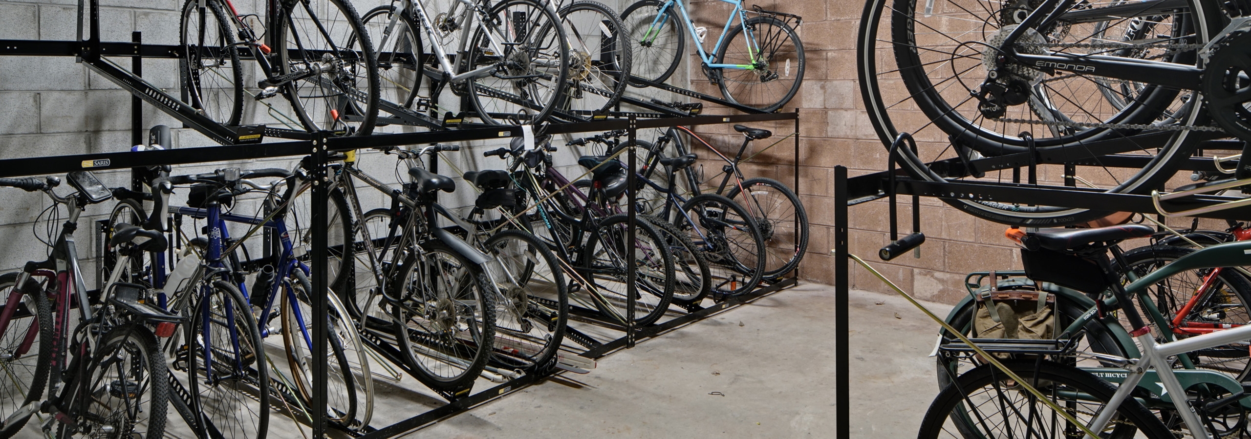 View of roughly twenty resident bicycles in a well lit storage area with cement flooring and white walls at AMLI Evanston
