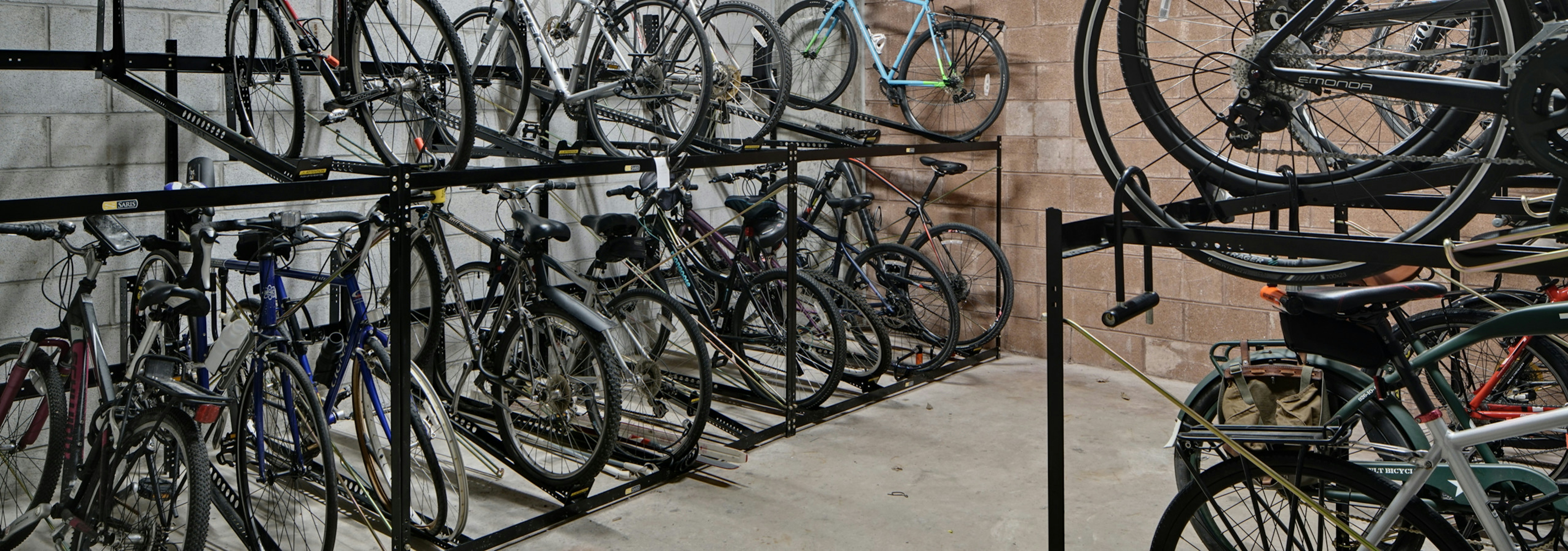 View of roughly twenty resident bicycles in a well lit storage area with cement flooring and white walls at AMLI Evanston