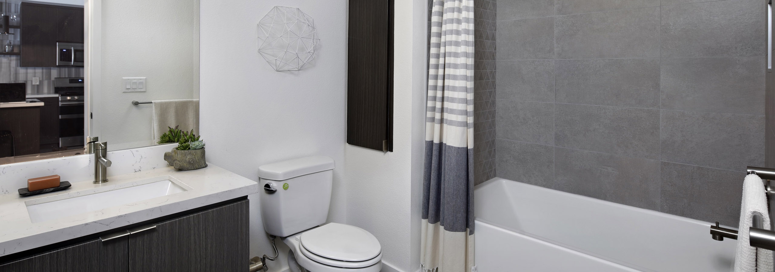 Interior of AMLI Park Broadway apartment bathroom with quartz countertop and large soaking tub with grey tile surround