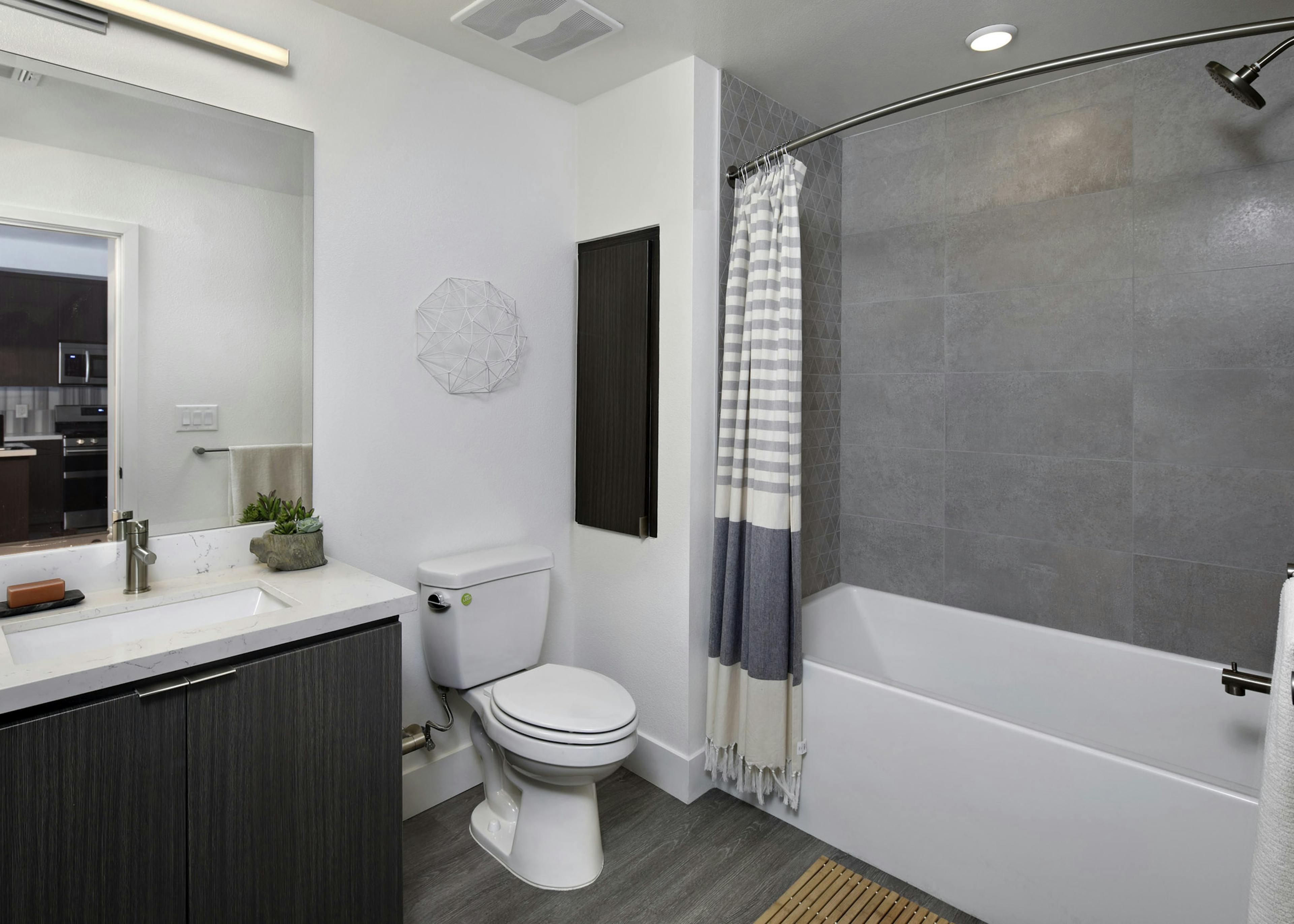 Interior of AMLI Park Broadway apartment bathroom with quartz countertop and large soaking tub with grey tile surround