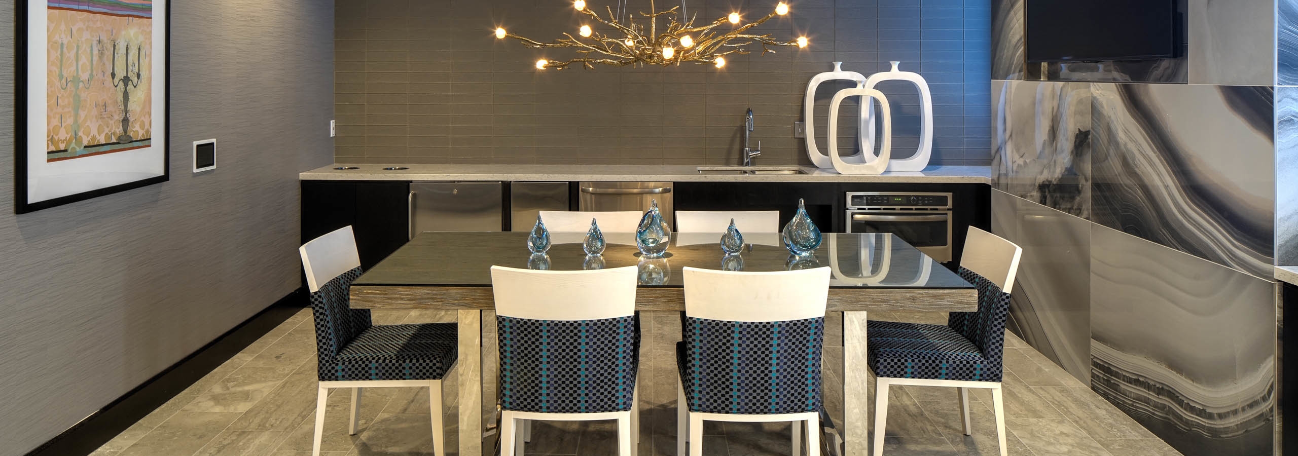 Interior of AMLI Deerfield gourmet kitchen with large dining table and blue and white chairs with decorative chandelier