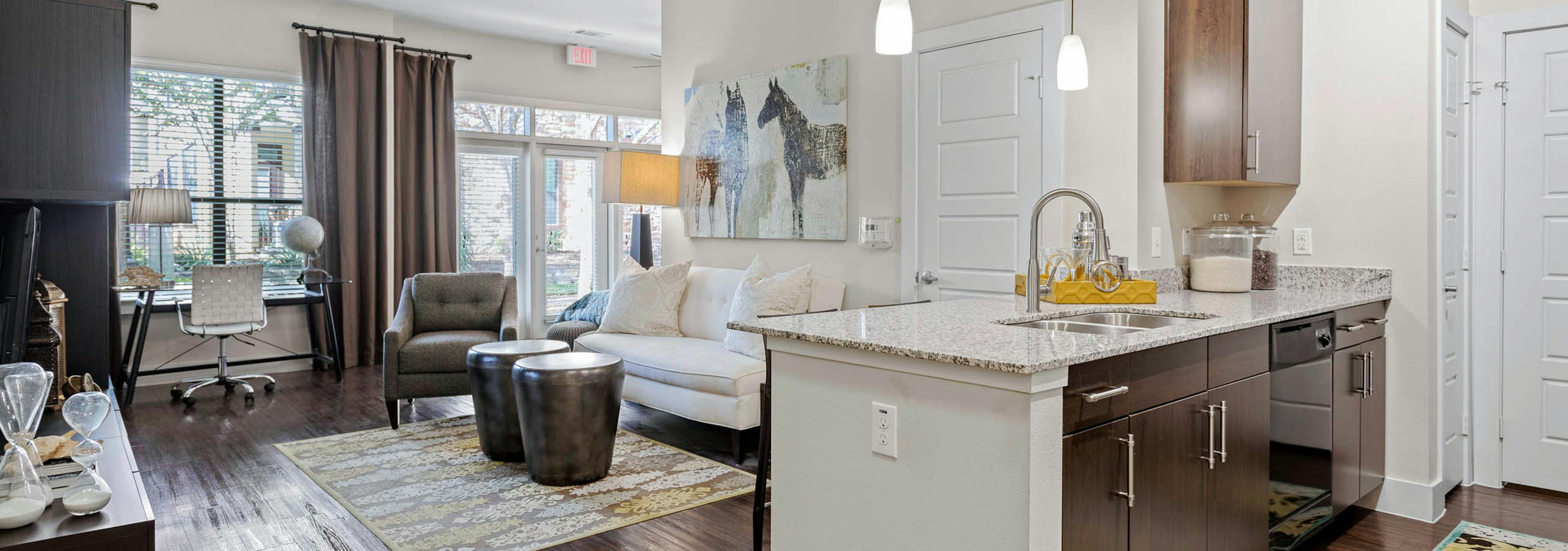 AMLI at Escena apartment with wood cabinets and granite countertops in the kitchen and a white sofa in the living room