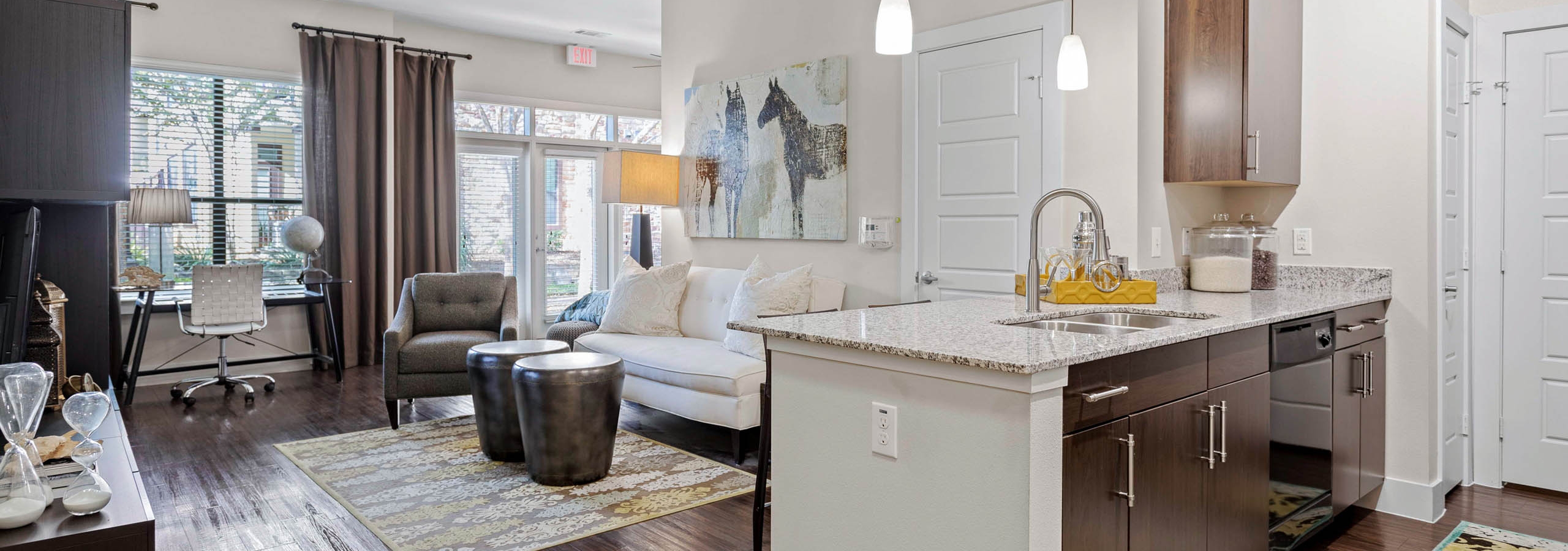 AMLI at Escena apartment with wood cabinets and granite countertops in the kitchen and a white sofa in the living room