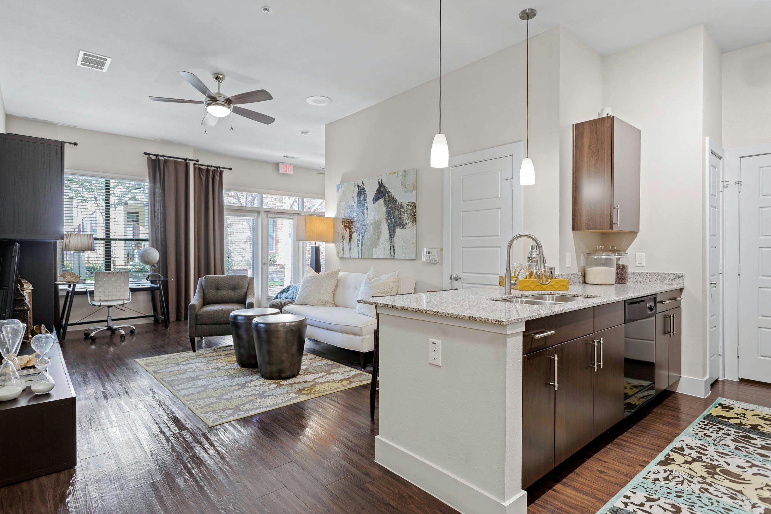 AMLI at Escena apartment with wood cabinets and granite countertops in the kitchen and a white sofa in the living room