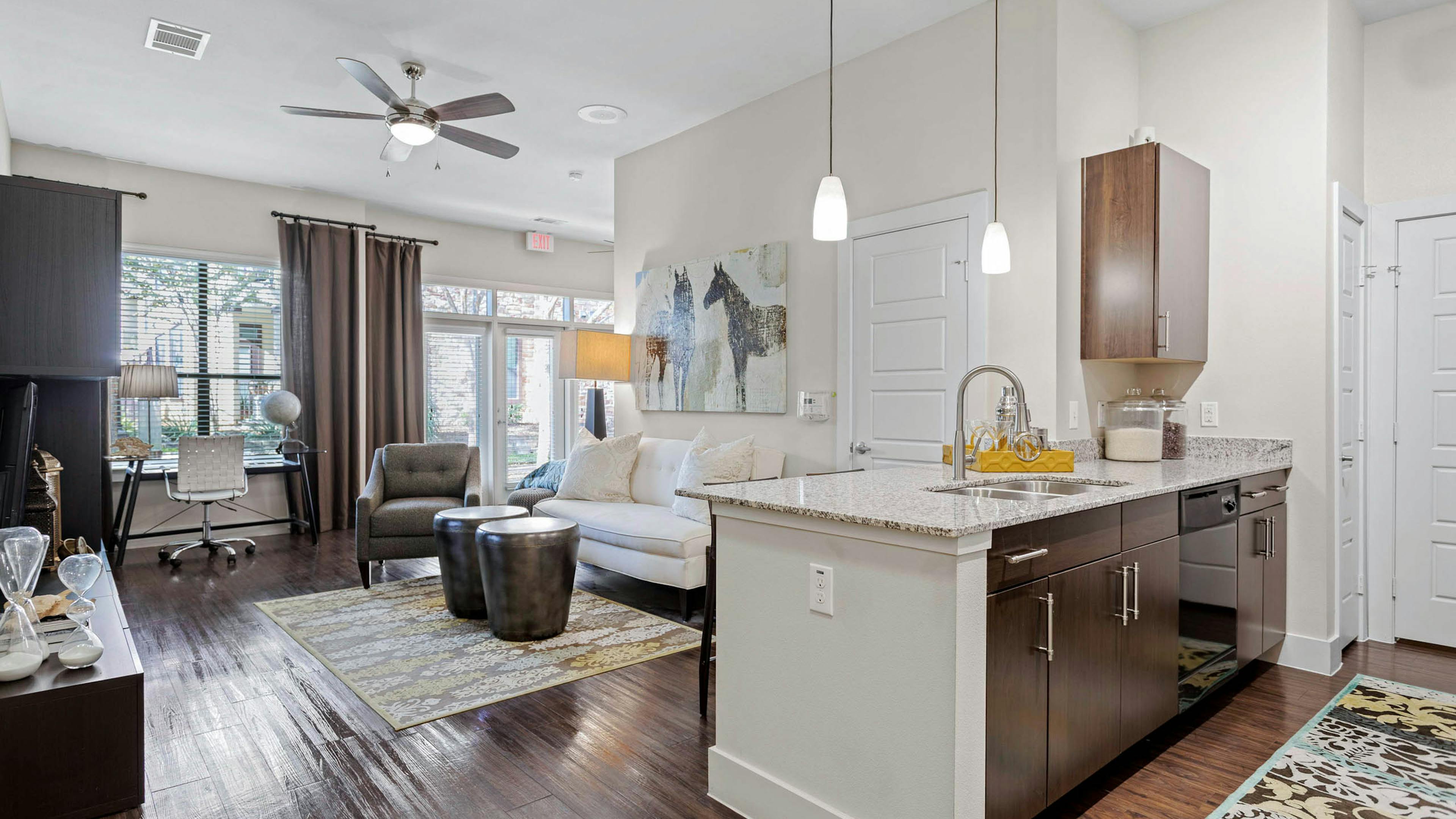 AMLI at Escena apartment with wood cabinets and granite countertops in the kitchen and a white sofa in the living room