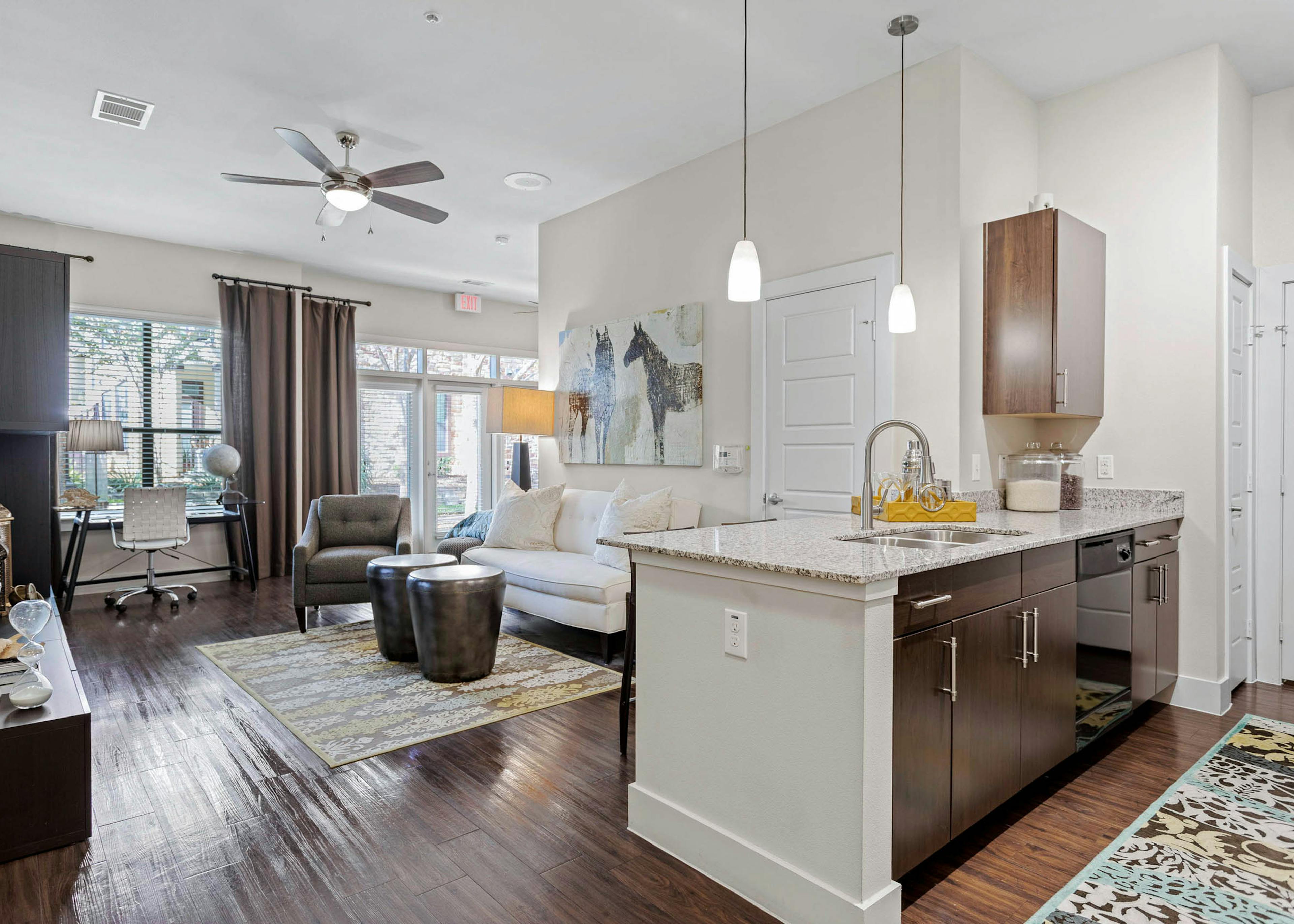 AMLI at Escena apartment with wood cabinets and granite countertops in the kitchen and a white sofa in the living room