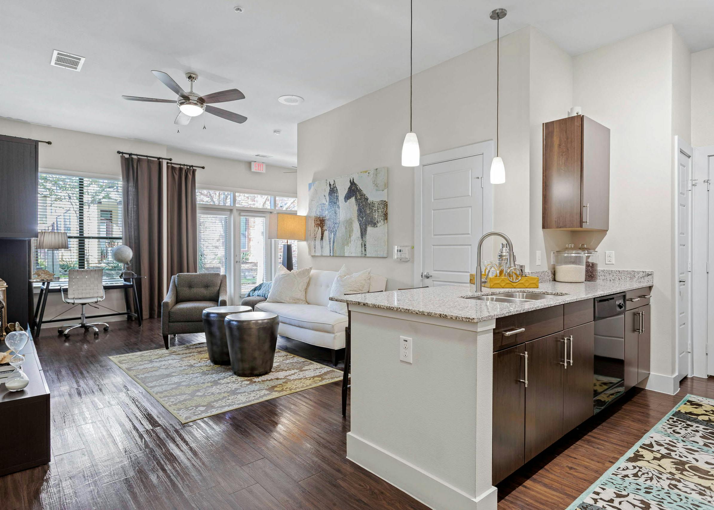 AMLI at Escena apartment with wood cabinets and granite countertops in the kitchen and a white sofa in the living room