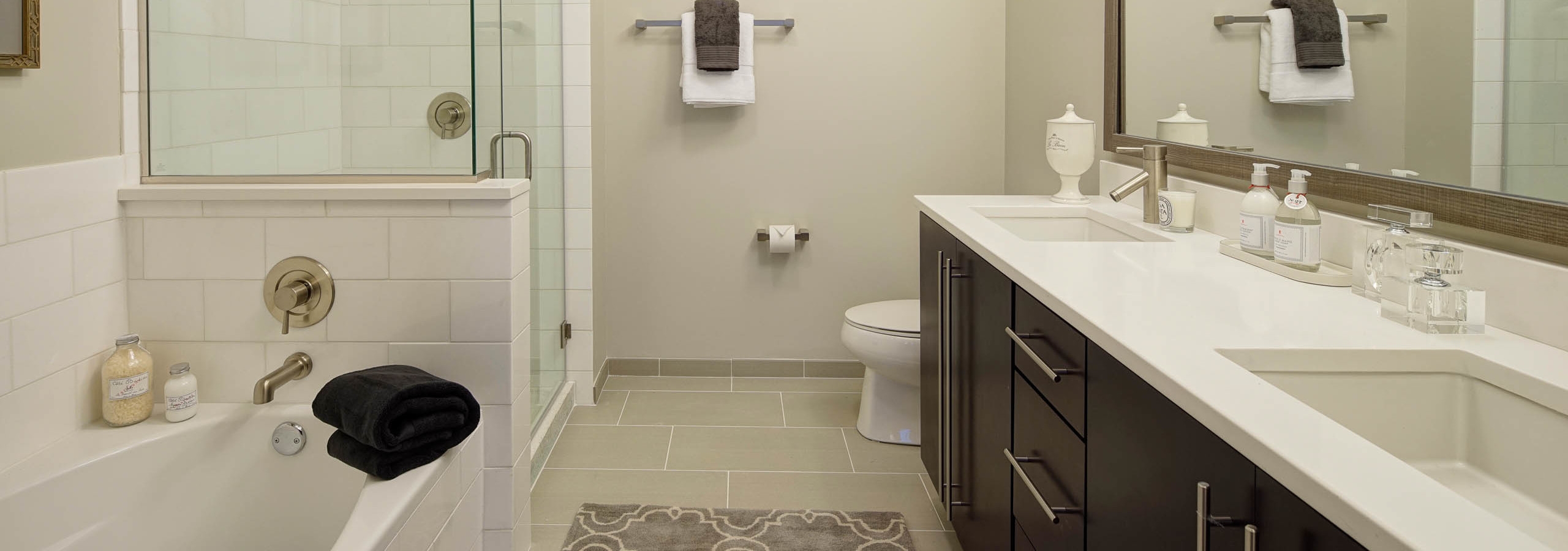 AMLI River North penthouse bathroom with a toilet and double vanity along one wall and a bathtub and shower along another