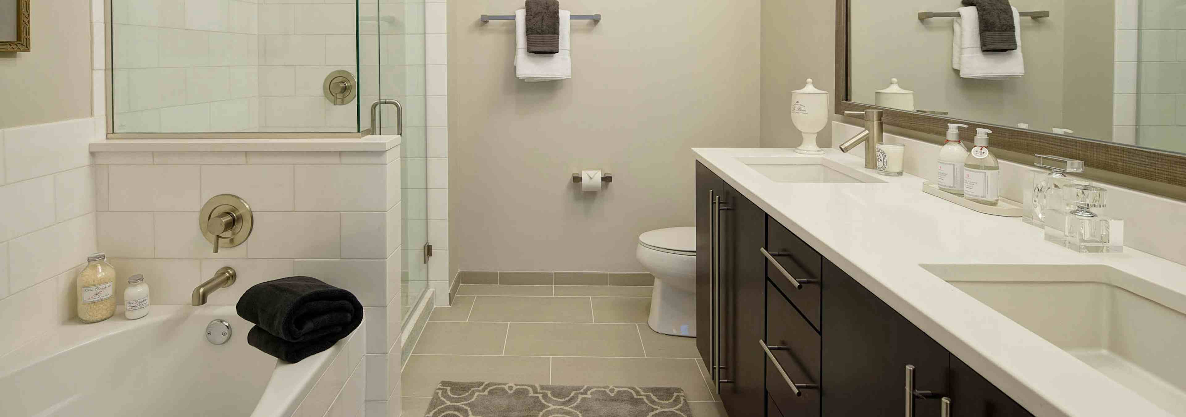 AMLI River North penthouse bathroom with a toilet and double vanity along one wall and a bathtub and shower along another