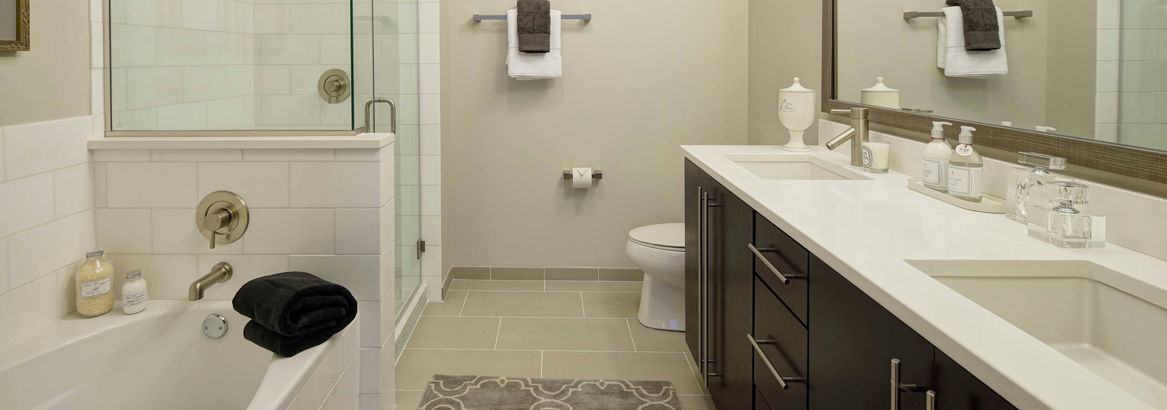 AMLI River North penthouse bathroom with a toilet and double vanity along one wall and a bathtub and shower along another