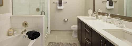 AMLI River North penthouse bathroom with a toilet and double vanity along one wall and a bathtub and shower along another