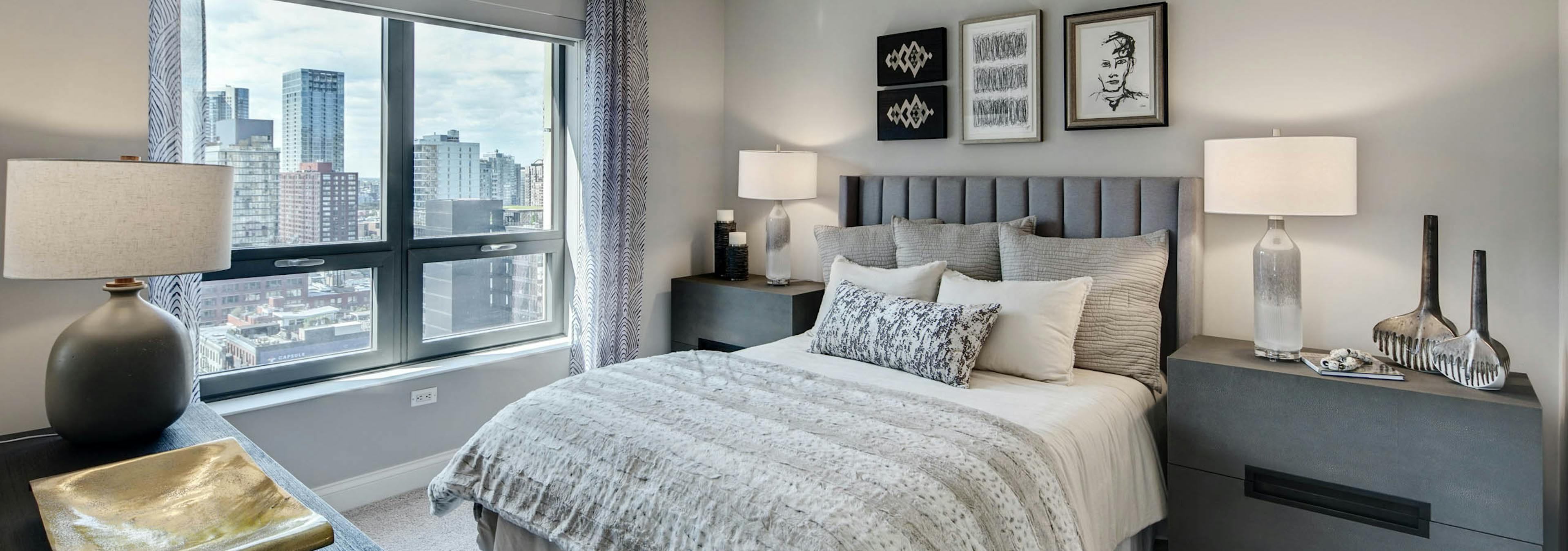 AMLI at River North apartment bedroom with grey furniture complimented by neutral bedding and carpeting with a bright window