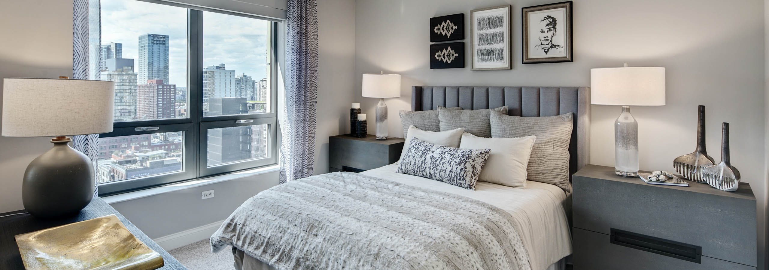 AMLI at River North apartment bedroom with grey furniture complimented by neutral bedding and carpeting with a bright window