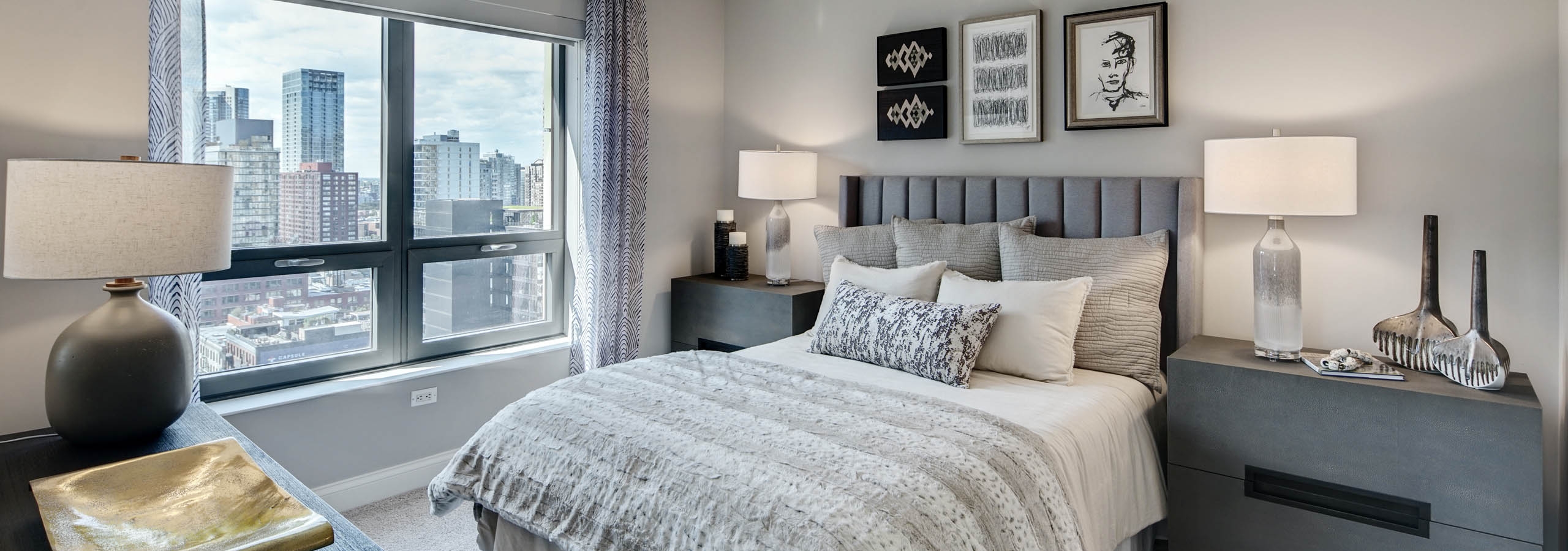 AMLI at River North apartment bedroom with grey furniture complimented by neutral bedding and carpeting with a bright window