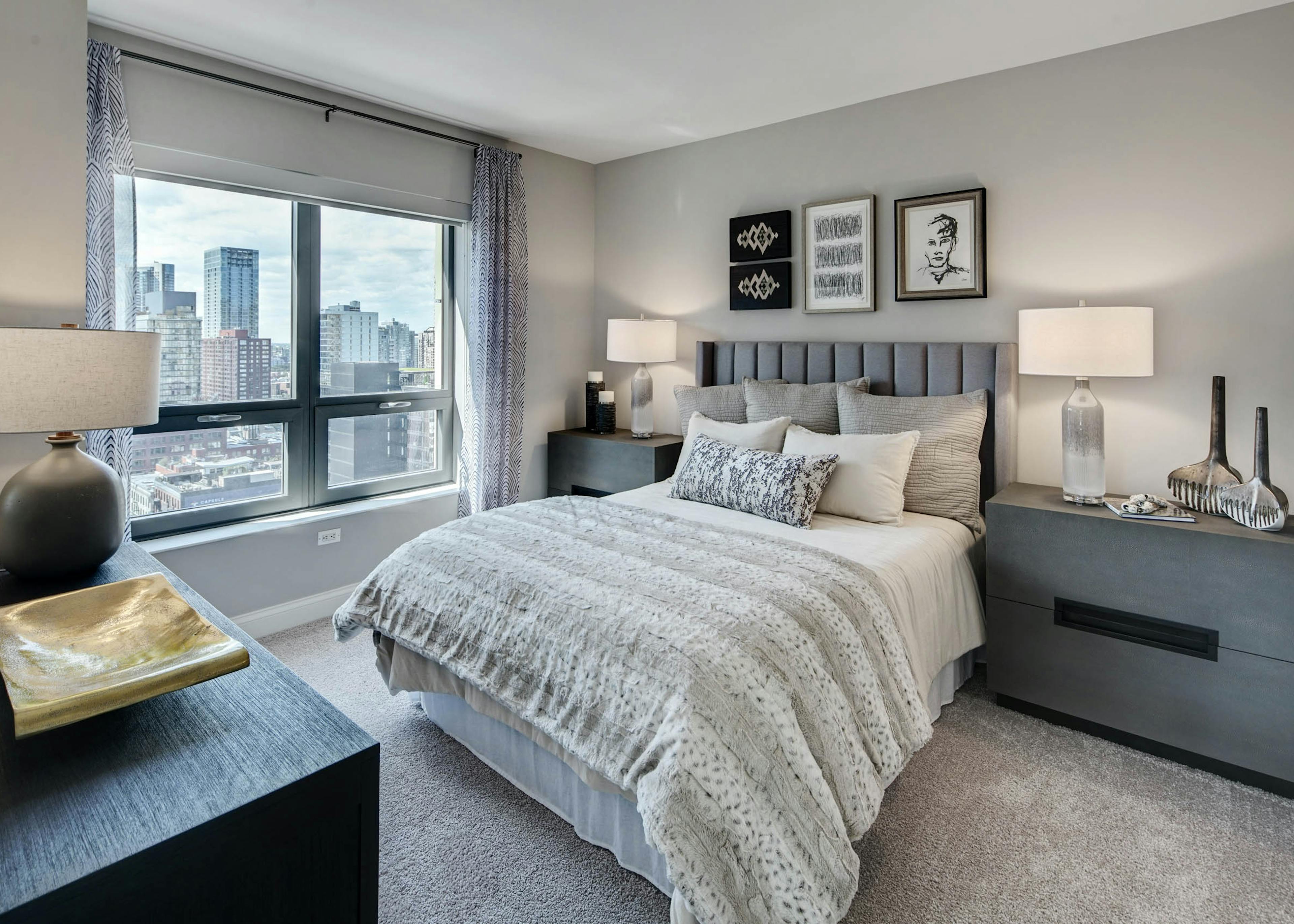 AMLI at River North apartment bedroom with grey furniture complimented by neutral bedding and carpeting with a bright window